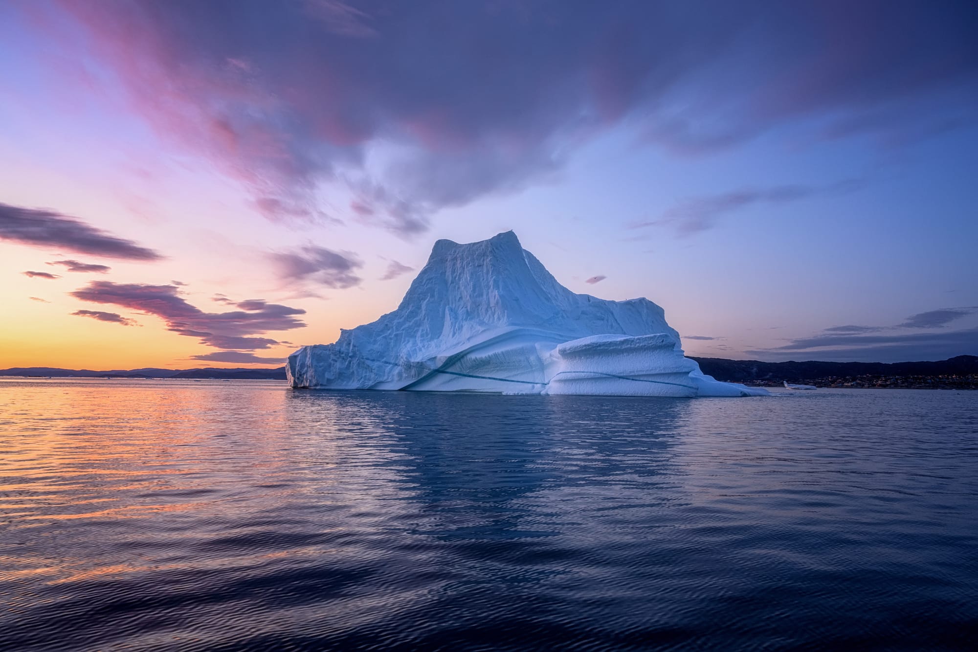 Iceberg monumentale illuminato dalla luce blu del sole di mezzanotte nelle acque di Ilulissat, Groenlandia.