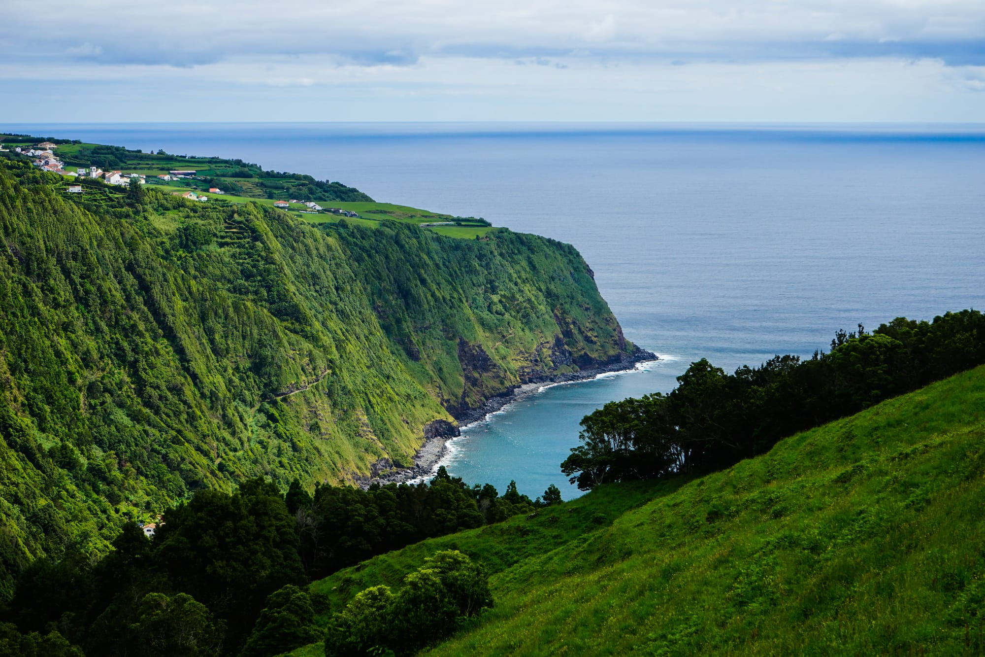 La verde costa di origine vulcanica delle isole Azzorre a picco sull'Oceano Atlantico, espressione del potente vulcanismo che ha forgiato la cultura locale.