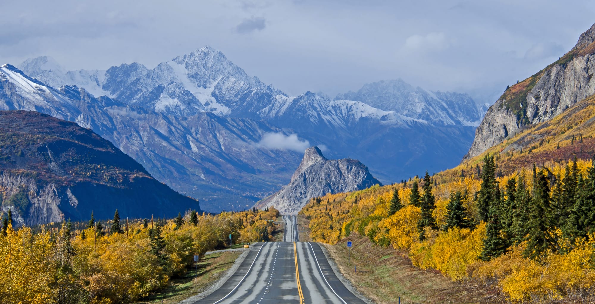Paesaggio autunnale in Alaska con i colori caldi della tundra attraversata da una strada solitaria che si dirige verso l'orizzonte infinito. | Viaggio in Alaska con Kel 12