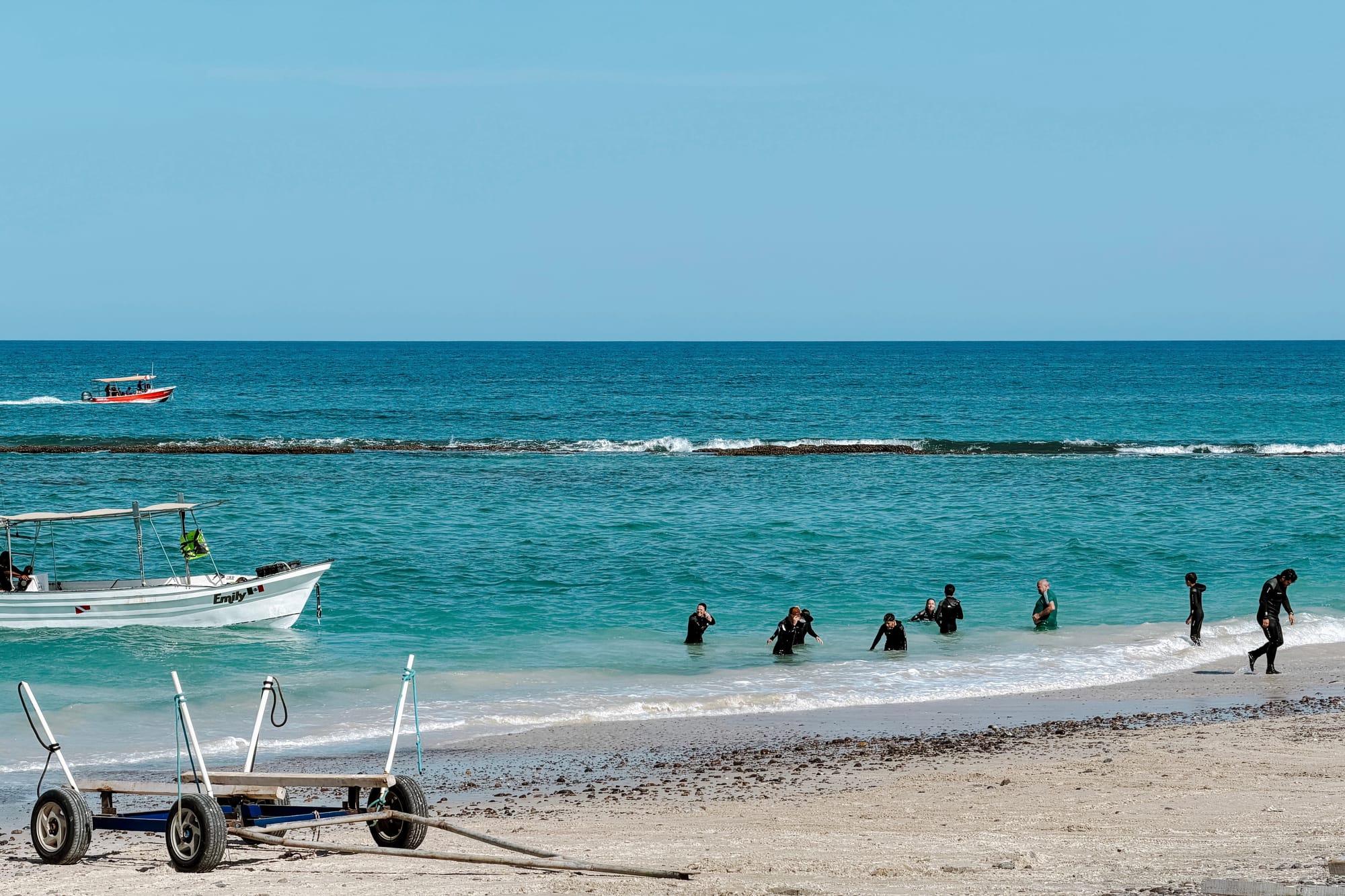 Turisti con attrezzatura da snorkeling camminano sulla spiaggia di Cabo Pulmo dopo un'escursione nella barriera corallina.